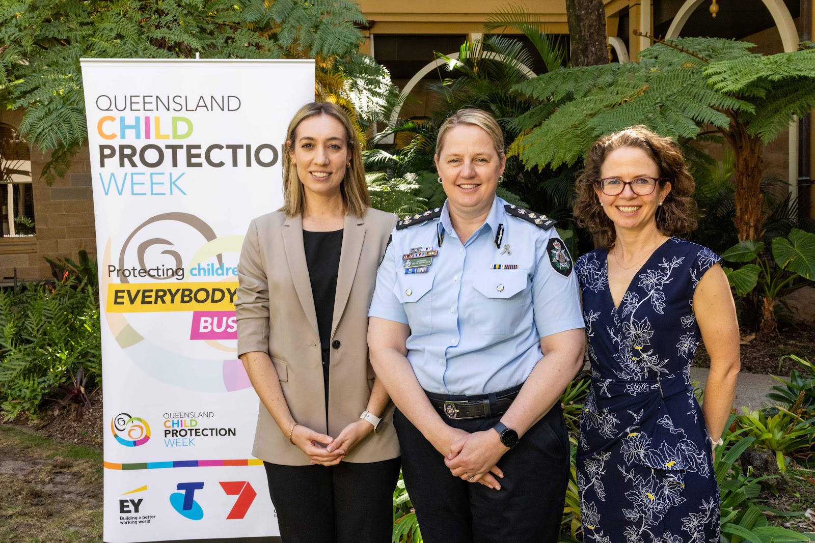 Simone McKeough, Commander Helen Schneider and Megan Emerson Elliott in front of Queensland Child Protection Week banner