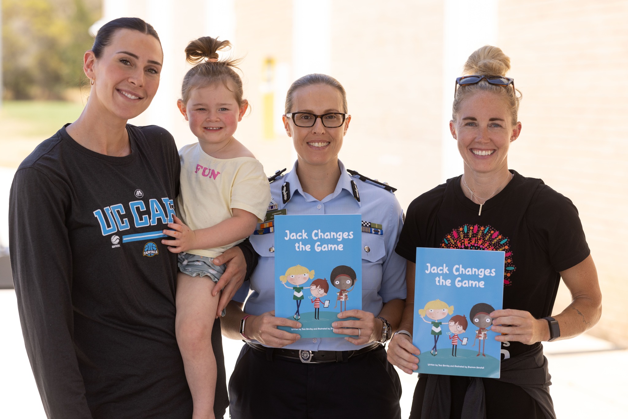 UC Capitals co-captains Alex Bunton (with daughter Opal) and Britt Smart, with Assistant Commissioner Hilda Sirec (centre) promoting the new book Jack Changes the Game.